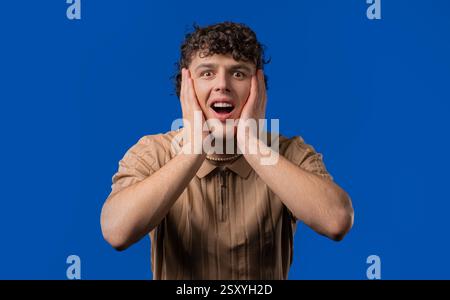 Shocked curly haired man glad, screaming WOW. Impressed guy, unbelievable Stock Photo