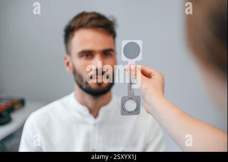 Holding tool. Man's vision checked by female doctor in the clinic by using special optometrist device. Stock Photo