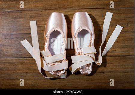 Ballet pointe shoes on a wooden floor, representing classical dance, art, and artistic hobbies Stock Photo