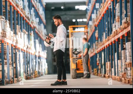 Using tablet to check the products. Storage worker is in the warehouse. Stock Photo