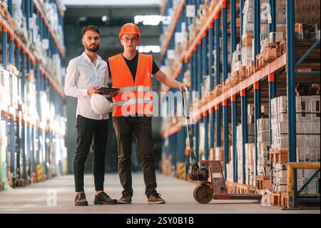 Talking to each other. Two storage workers is in the warehouse. Stock Photo