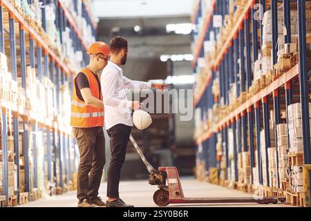 Standing and working together. Two men in storage is in the warehouse. Stock Photo