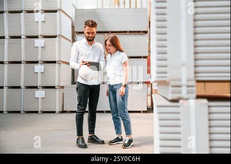 Young manager in formal clothes is working with woman in the warehouse. Stock Photo