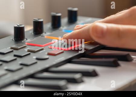 Woman playing MIDI keyboard with control knobs and pads, close-up. Making music. Stock Photo
