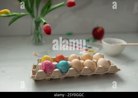 A vibrant array of decorated eggs, tulips, and an apple on a bright table, creating a festive atmosphere. High quality photo Stock Photo