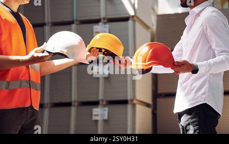 Holding hard hats. Standing together. Two storage workers is in the warehouse. Stock Photo