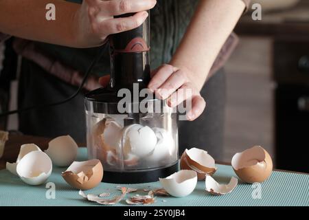 Preparing Eggshell Powder. Woman grinds eggshells with blender. Calcium supplement, cracked eggshell, natural compost ingredient, broken eggshell Stock Photo