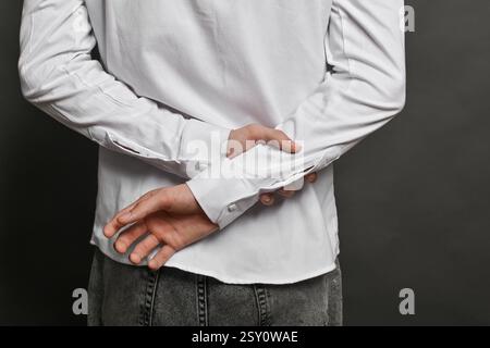 A man's hands clasped behind his back. He wrapped his hand around the wrist of his other hand. Stock Photo