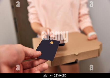 man paying for pizza with black credit card at doorway, close-up Stock Photo