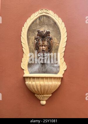 Medusa Wall Fountain on Textured Terracotta Wall Stock Photo