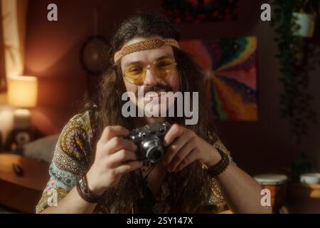 Smiling Man Holding Camera Sitting in Cozy Room Stock Photo