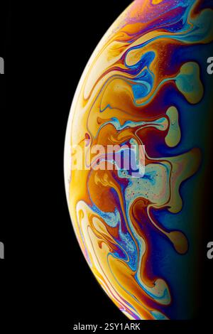 Close-up of soap bubble surface on black background. Bright colors and abstract pattern. Stock Photo
