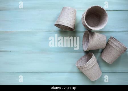 Group of empty peat pots over a green rustic table with copy space. Table top view. Stock Photo