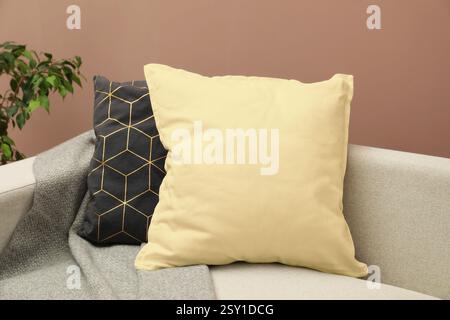 Pillows on sofa near pastel brown wall, closeup Stock Photo