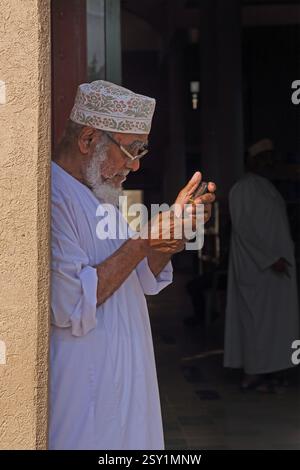 Omani Man Texting on Mobile Phone at Nizwa Market (Souk) Oman Stock Photo