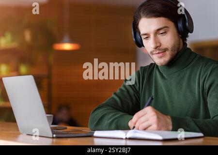 Concentrated guy with headset studying online, using laptop Stock Photo