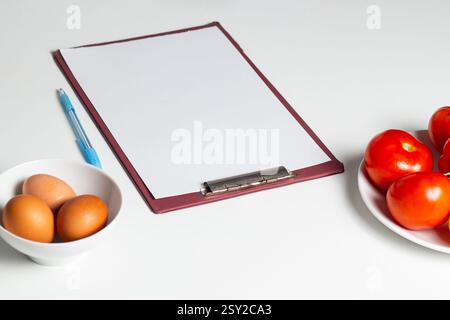Blank mock up of diet plan, diet menu. Paper with copy space on table with vegetables and eggs. Preparing healthy eating plan. Stock Photo