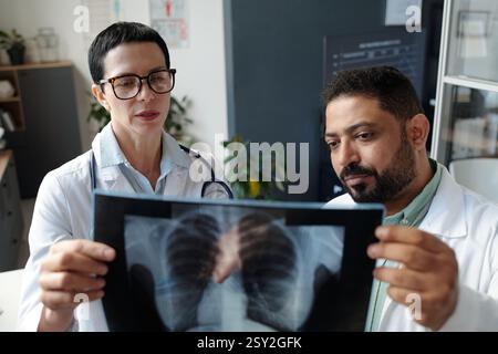 Two Doctors Looking at Chest X Ray Images in Clinic Office Discussing Patient Diagnosis Stock Photo