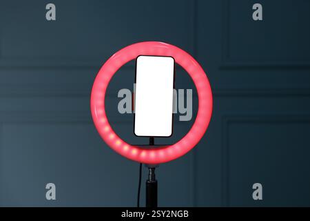 Ring lamp with smartphone against wall indoors Stock Photo