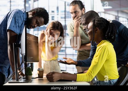 IT staff members discussing and working, testing and deploying programs and systems. Team of software engineers checking code, sitting at desk chair in office, doing brainstorming Stock Photo