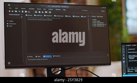 Asian programmer seen typing code for a user interface design on dual monitors, working in a digital workspace. Woman coder working on software engineering and front end development. Camera B. Stock Photo