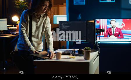 Developer holding disposable cup of coffee entering office to implement security measures, protecting company systems and data. IT worker starting job shift, testing and debugging code, camera A Stock Photo