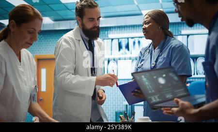 Healthcare team collaborates on human anatomy and diagnostic procedures. Group of specialists meeting in office to discuss treatment plans after radiology results. Disease prevention. Camera B. Stock Photo