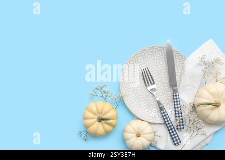 Beautiful table setting with fresh pumpkins and gypsophila flowers on blue background Stock Photo