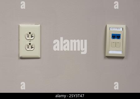 Wall with network jack on right and electric outlet on left Stock Photo