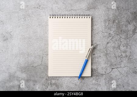 Top view of notebook and ballpoint pen on stone background Stock Photo