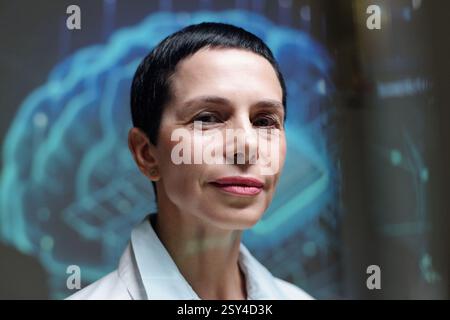 Closeup portrait of smiling mature woman as expert female scientist looking at camera with brain projections in background Stock Photo