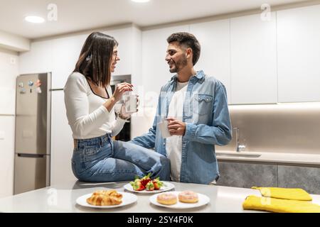 Young couple sharing a moment together while having breakfast and coffee in their modern kitchen Stock Photo
