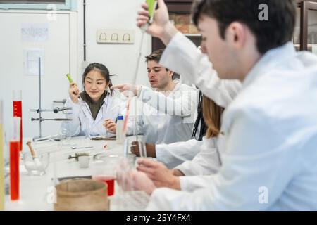 University students in lab coats conducting a chemistry experiment, collaborating and learning together Stock Photo