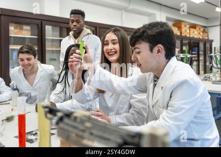 Diverse group of university chemistry students conducting an experiment in a lab, using lab coats and equipment, showcasing teamwork and scientific in Stock Photo