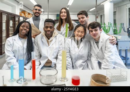 Group of diverse university students and their teacher posing together in a chemistry laboratory, showcasing teamwork and scientific exploration Stock Photo