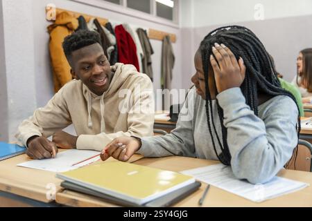 Two high school students working together on a project, sharing ideas and collaborating in a classroom setting Stock Photo