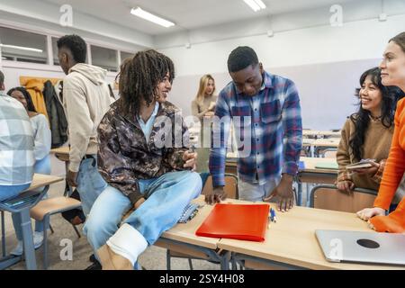 Multi ethnic university students collaborating on a project, discussing ideas and sharing knowledge in a classroom setting Stock Photo