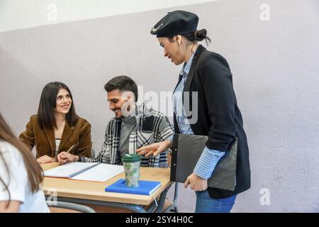 University students collaborating on a project, receiving guidance from their professor in a classroom setting Stock Photo