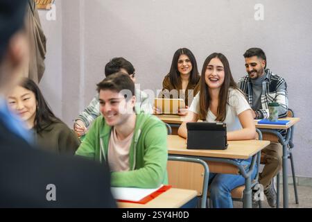 Multi ethnic university students attending a lecture and using digital tablets, enjoying learning and academic pursuits Stock Photo
