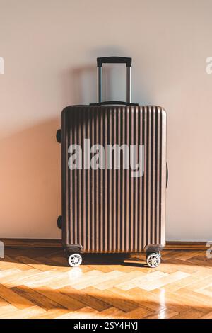 Suitcase for travel and vacation against light wall in room on sunny day. High quality photo Stock Photo