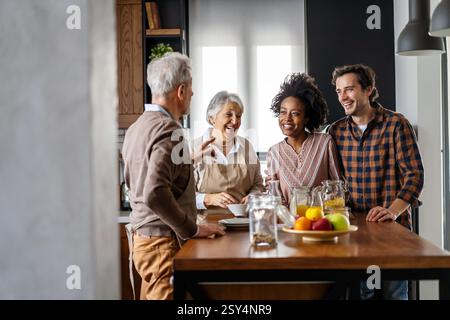 Multi generation multiethnic family having fun, talking around a festive kitchen table. Stock Photo