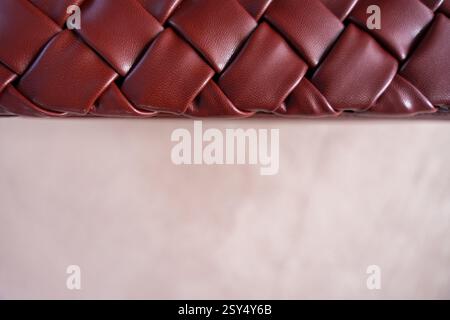 Close up of burgundy woven faux leather handbag on neutral suede background with copy space Stock Photo