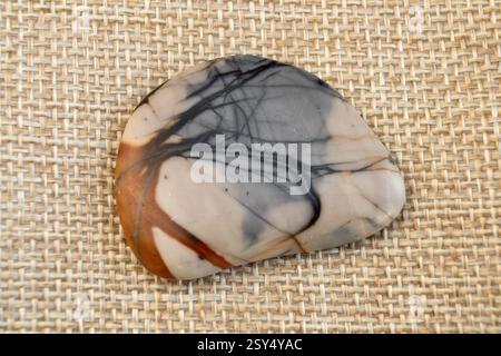 one small natural jasper picasso stone, brown and grey on craft paper background top view Stock Photo