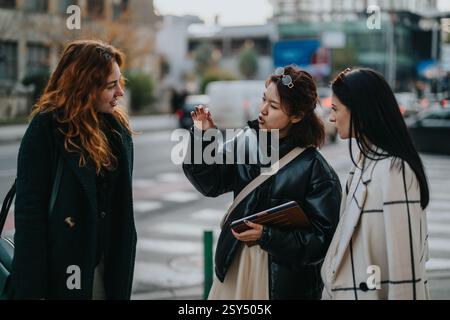 Group of three businesswomen collaborating outdoors on a busy street Stock Photo