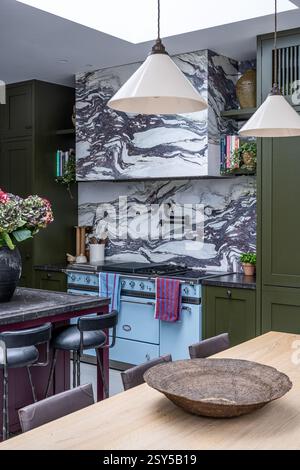 Pendant lights above table with aubergine and olive green paintwork in contemporary redesign of West London home. Stock Photo