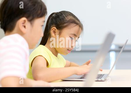 Two Children Using Laptops In A Classroom Stock Photo