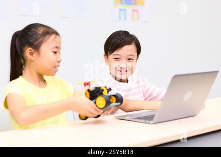 Two Children Sitting At A Table With A Laptop Stock Photo