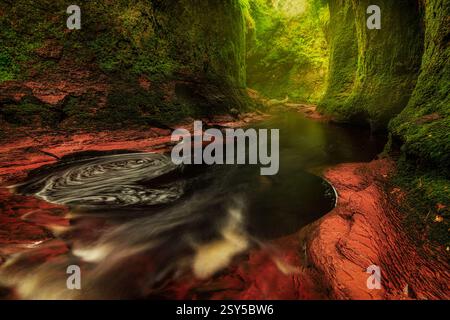Beautiful landscape image of Finnich Glen, The Devil's Pulpit with beautiful sunlight in the canyon and on the green walls on the rocks Stock Photo