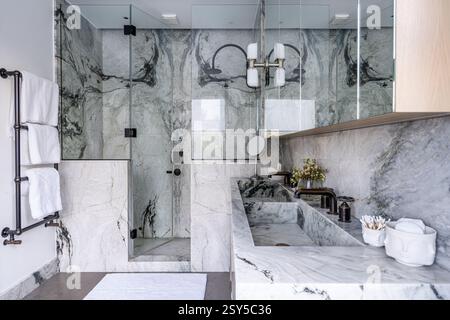 Walk in shower and double basin with mirrored cabinet in marble bathroom in contemporary redesign of West London home. Stock Photo