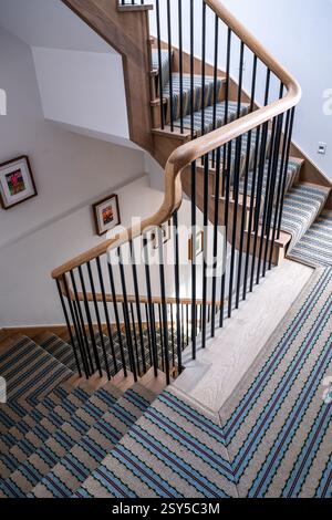 Striped carpet runner on staircase in contemporary redesign of West London home. Stock Photo
